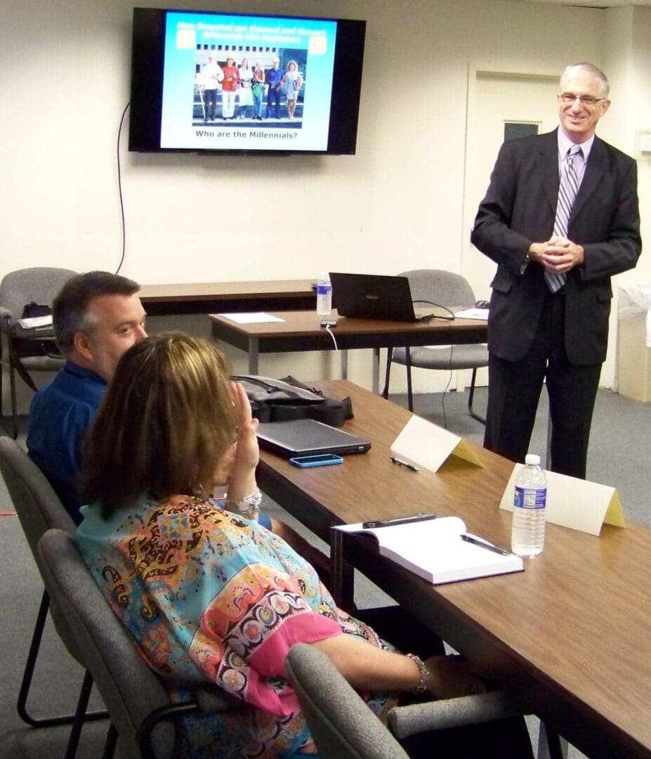 Seminar instructor Denis Sweeney smiling as he talks with 2 attendees